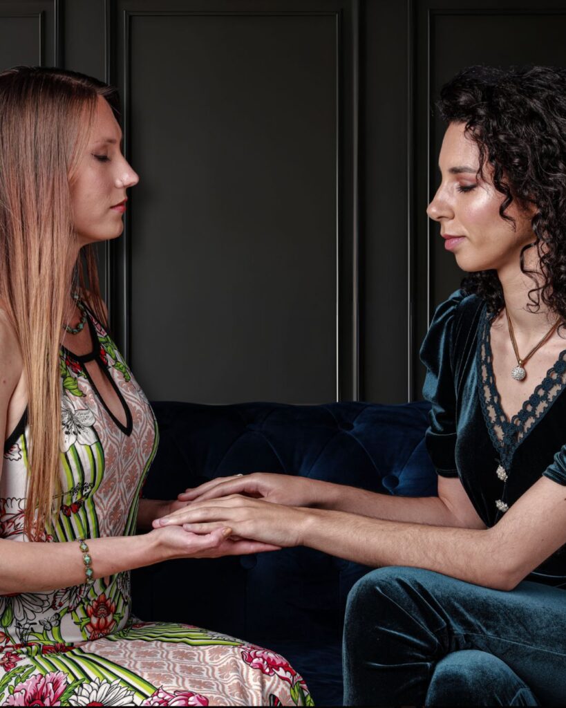 two women holding hands in a healing session